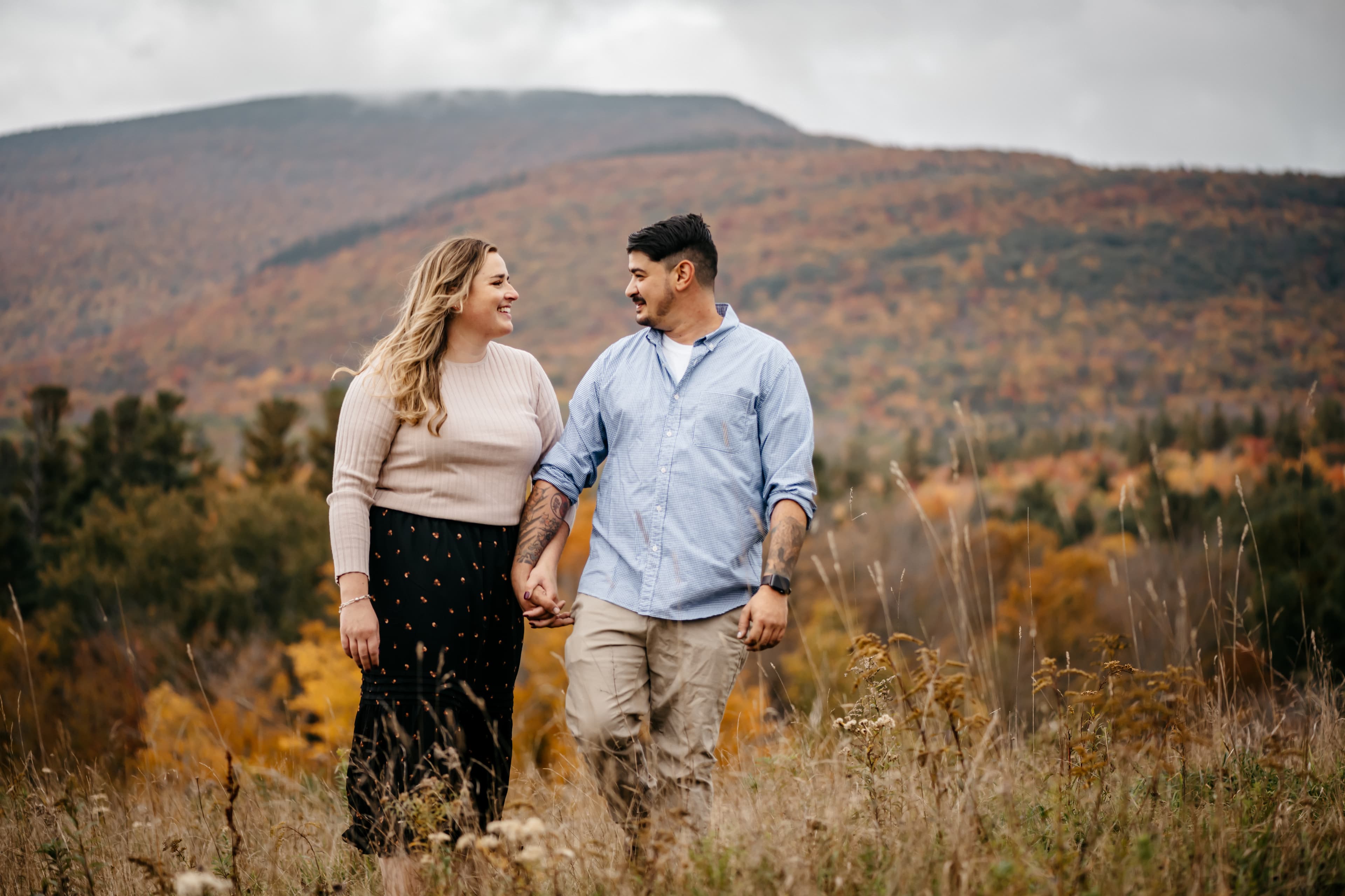Engaged couple walking through an Upstate New York meadow in autumn
