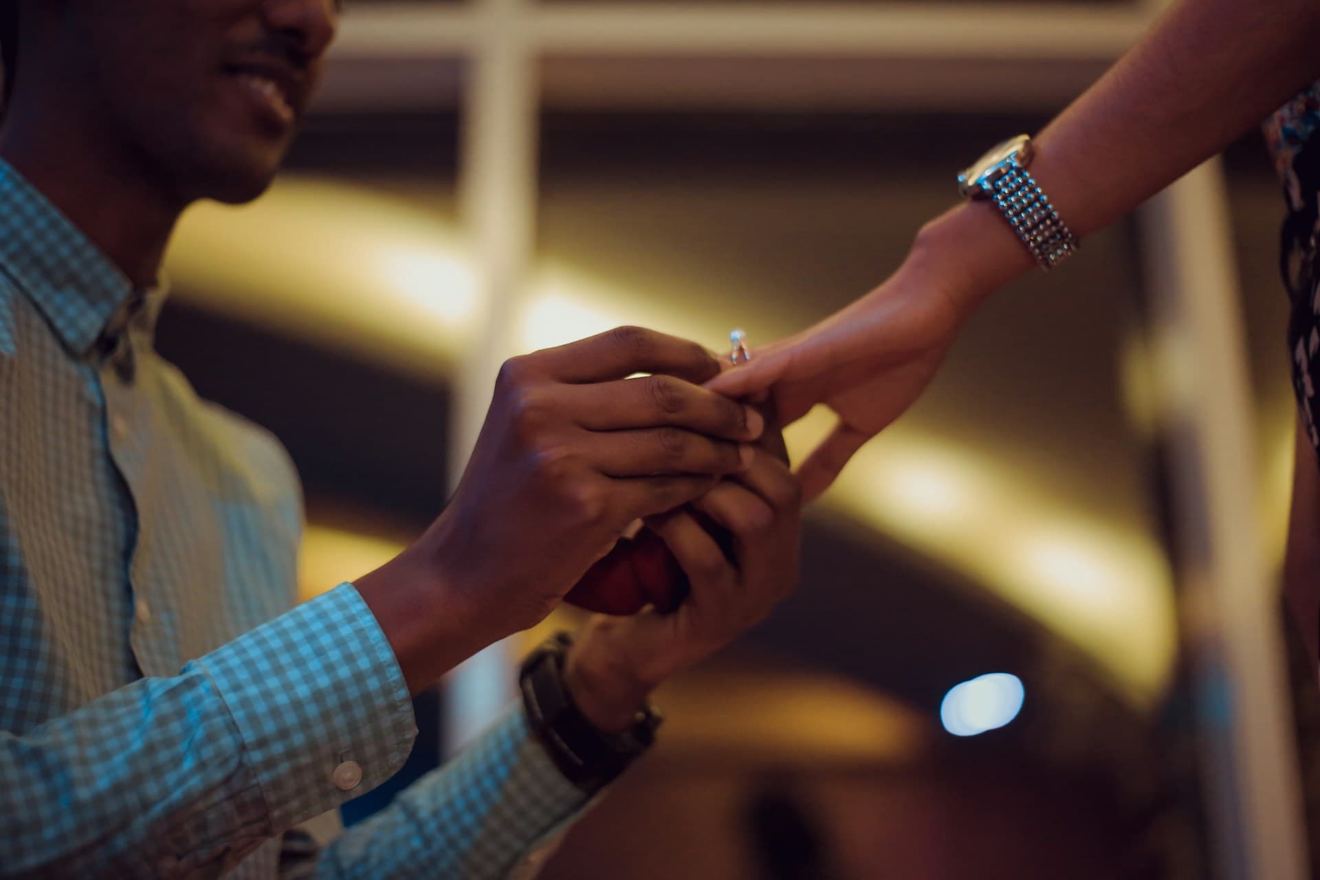 Close-up of an engagement ring during a warm, candlelit proposal