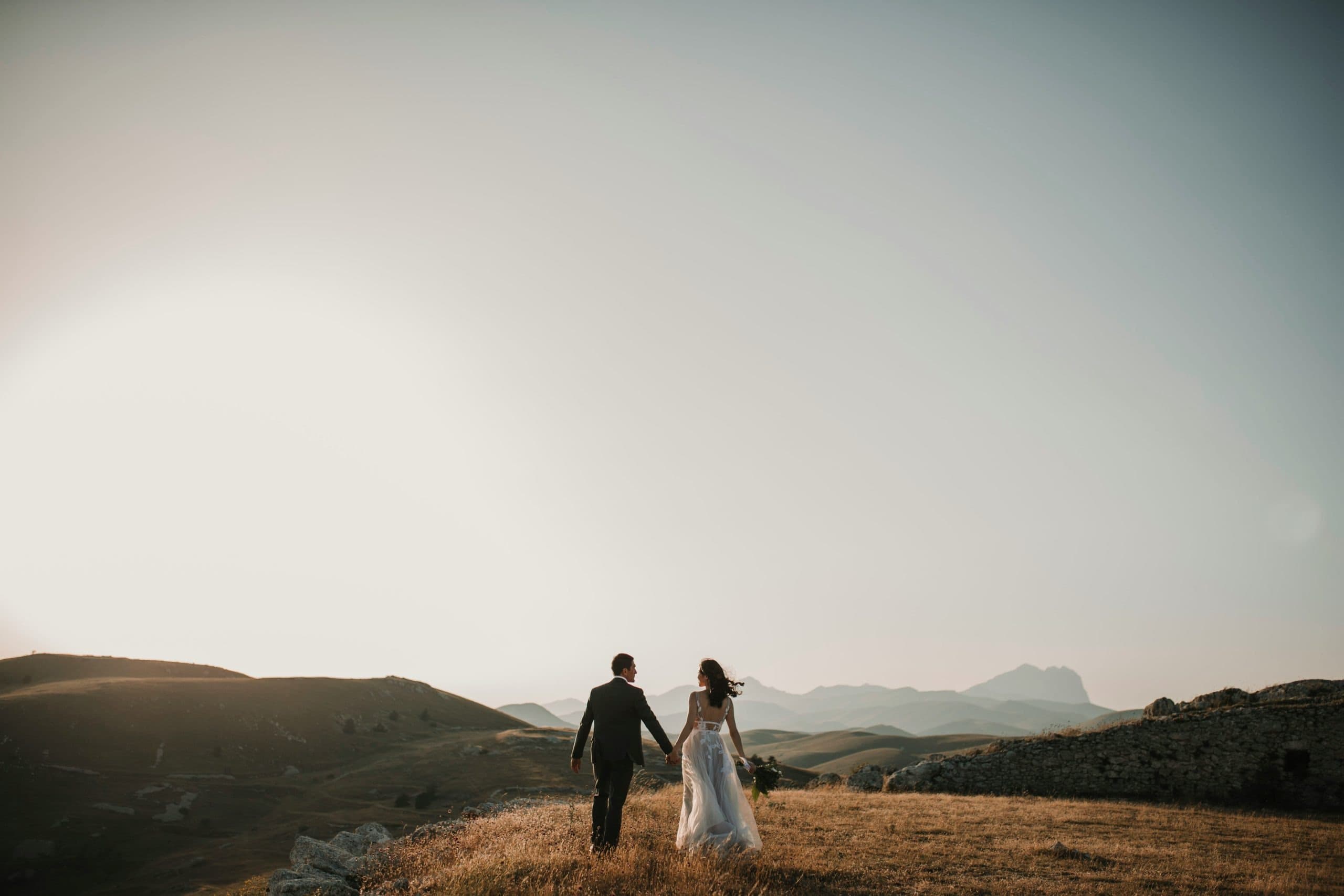 Bride and groom walking on a hilltop at sunset in Upstate New York