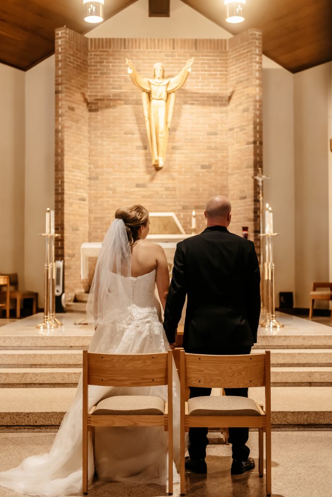 A bride and groom stand at the alter in a church knowing how much to get married in new york
