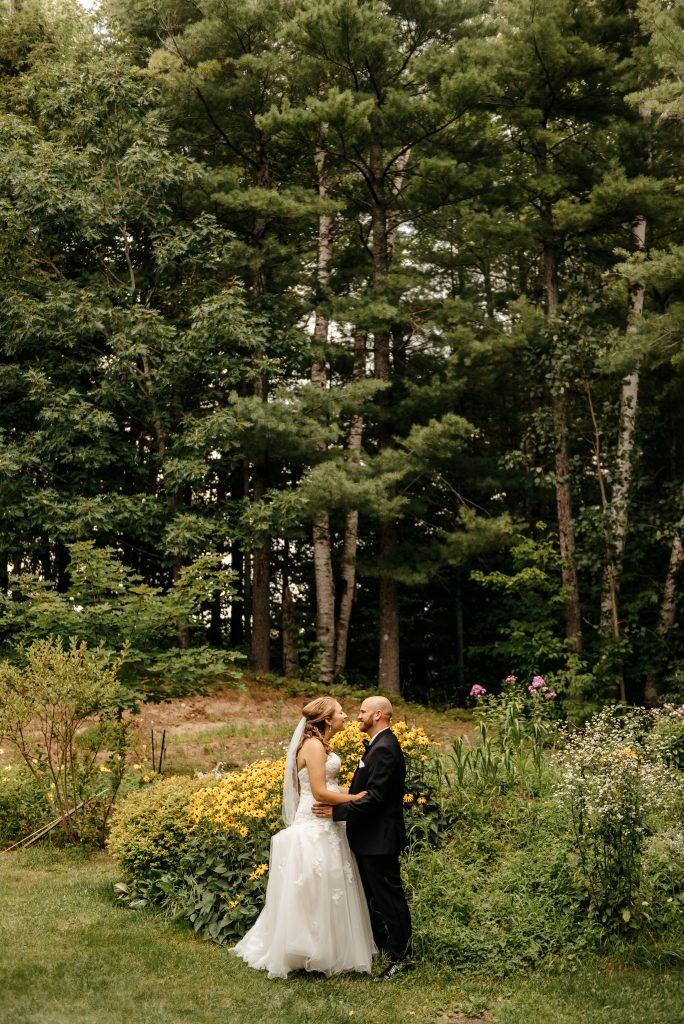 A bride and groom know how to get married in new york as they hold each other in a lush garden outside their wedding venue
