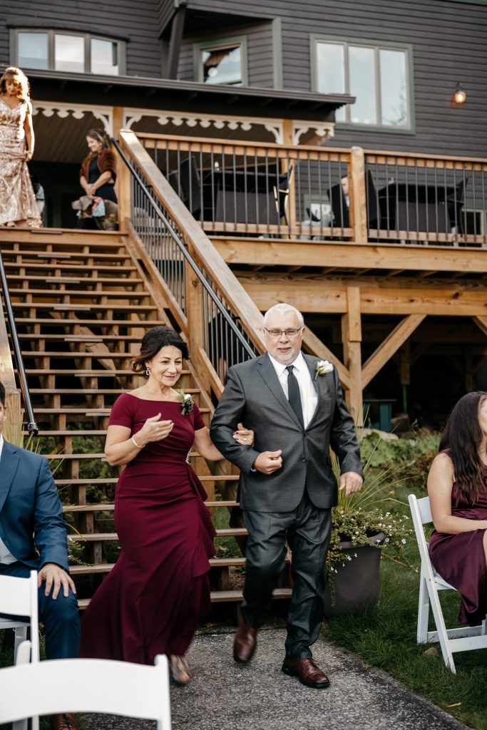 A mother of the groom in a burgundy dress is escorted down the aisle during a wedding that is the
average cost of a wedding in ny