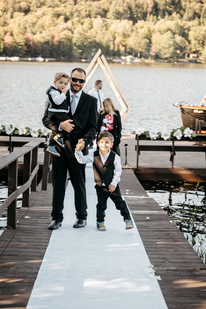 A groomsman and his two kids are dressed in black suits and know the average cost of a wedding in upstate ny