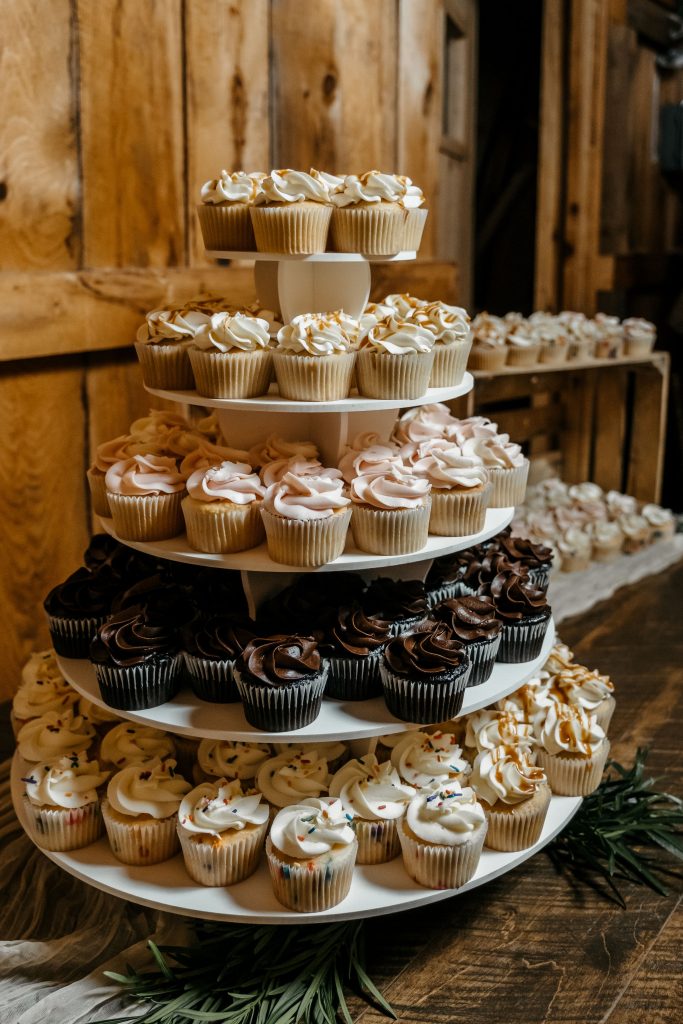 Multiple flavors of cupcakes are displayed on a cupcake stand at one of the Upstate New York wedding venues
