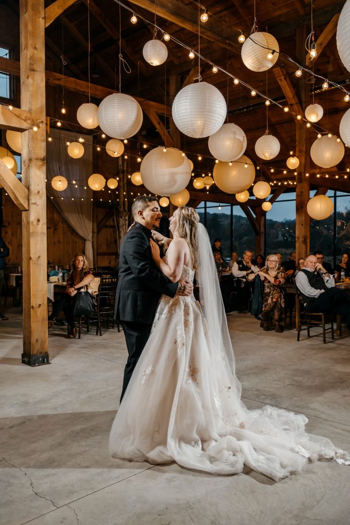 A bride and groom share a first dance under paper lanterns at their
Upstate New York wedding venue
