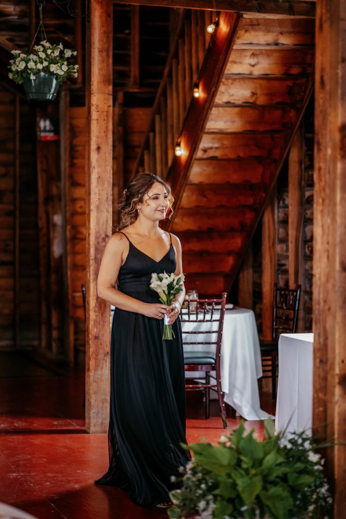 A bridesmaid smiles in a black dress at an Upstate New York wedding venue