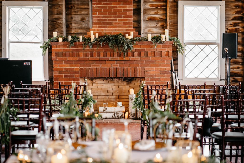 Wooden chairs are neatly arranged facing a brick fireplace at one of the
upstate new york barn wedding venues