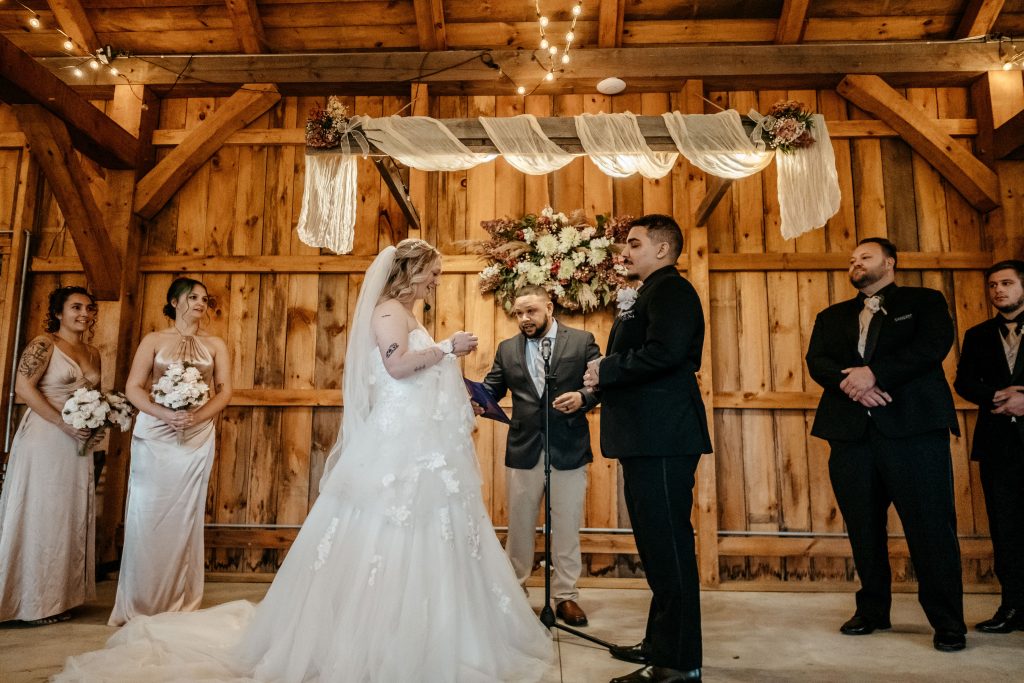 A bride reads her vows to her groom while a photographer takes
Gables and Gardens photos