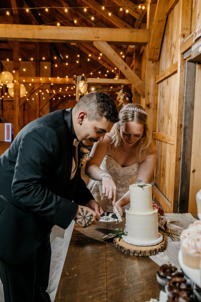 A bride and her groom cut their wedding cake at their wedding at Gables and Gardens Granville NY
